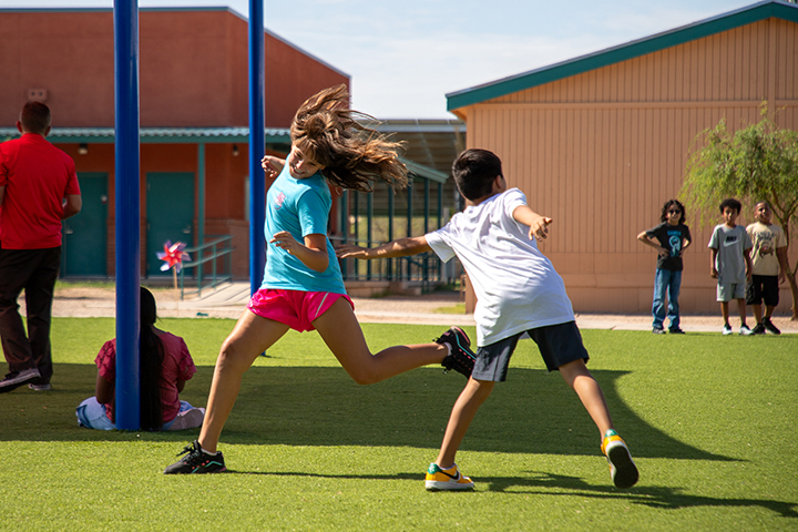 A girl and boy play tag on the playground