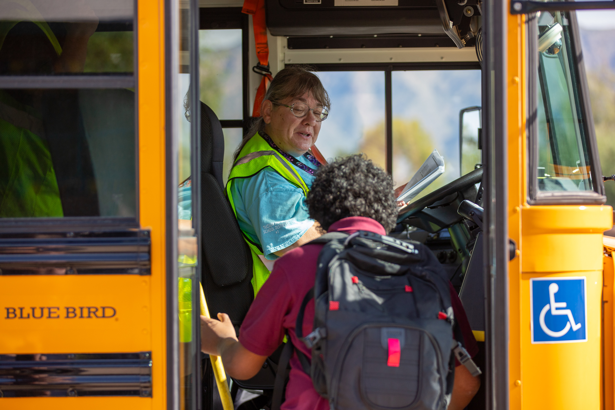 A bus driver smiles as a boy gets on her bus