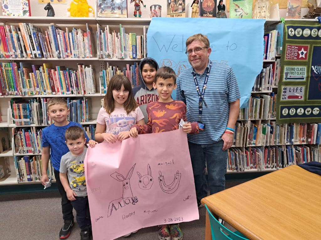 Students and their teacher pose with a poster they drew